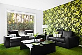 Dark leather sofa set against green retro wallpaper combined with green velour carpet; large picture window showing view of garden