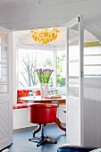 View into bright room with orange, retro swivel chair at round wooden table