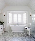 White, wood-panelled bathroom with Carrara marble floor and free-standing, white bathtub