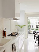 weiße Designerküche mit integrierten Spülbecken in Corian Arbeitsplatte; Essplatz mit Thonetstühlen