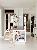 Bar stools at island counter in minimalist, white designer kitchen