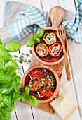 Stuffed vegetables in bowls on a wooden board (seen from above)