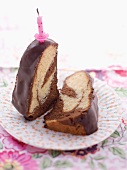 Two slices of marble cake with chocolate glaze and a birthday cake candle