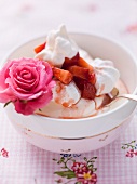 Quark with meringues and strawberries in a bowl garnished with a rose