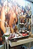 Ladies' shoes displayed on vintage bureau and shelves against wall painted with Baroque angel motif