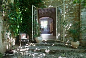 Offene Terrassentüren eines mediterranen Landhauses aus Naturstein und Blick in Wohnraum