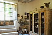 Vintage Vitrinenschrank mit Geschirr neben Terrassentür im Wohnraum eines schlichten Landhauses