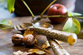 An arrangement of walnuts and cutlery with an apple in the background