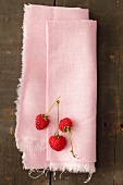 Three raspberries on a pink linen cloth