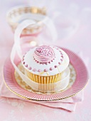 A cupcake with icing and pink decorations