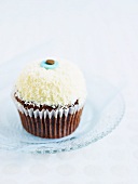 A cupcake decorated with coconut sprinkles and butter cream