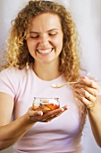 A young woman laughing and eating a peach dessert