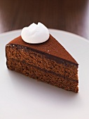 A slice of chocolate cake with a dollop of cream