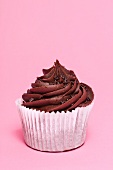 A chocolate cupcake on a pink surface
