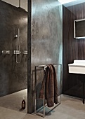 Designer Bad mit Handtuchhaltergestell neben Wand aus Beton vor Duschbereich
