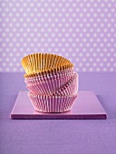 Pink and yellow muffin cases against a purple surface