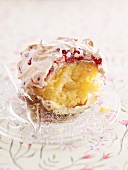 A cupcake topped with redcurrant meringue with a bite taken out