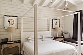 White canopied bed with antique bedside tables and upholstered window seat with practical drawers