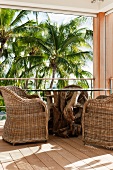 Balkonecke mit rustikalem Tisch, bequemen Korbsesseln und Blick auf Palmen