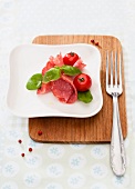 Sliced salami with basil and tomatoes