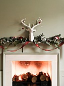 Fireplace with logs, tealights, Christmas decorations and ornamental stag's head