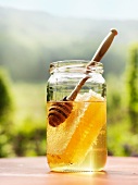 Ein Glas Honig mit Honigwabe und Honiglöffel
