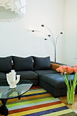 Coffeetable auf gestreiftem Teppich und dunkle Couchkombination in minimalistischem Wohnzimmer