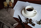 Schreibpapier und Kugelschreiber neben Tasse Kaffee auf Tisch