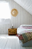 Simple attic bedroom with white-painted boards on walls and floor