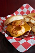 Cheddar Cheeseburger with Onion Ring and Barbecue Sauce on a Toasted Bun with Chips