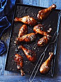 Marinated chicken legs with sesame seeds, on a baking tray