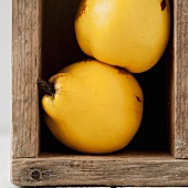 Two quinces in a wooden crate