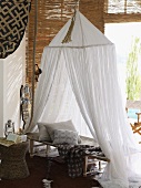 Bed with gauze canopy in room decorated in African style