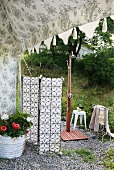 Detail of tent - potted flowering plants in front of screen and view of garden