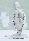 Key and daisy chain hanging on white china figurine