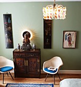 Backlit mirror as halo behind figure of Buddha; antique, Oriental cabinet flanked by classic chairs