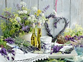 An arrangement of lavender: a heart-shaped lavender wreath, a jar of lavender sugar, two bottles of lavender and olive oil, wild chervil and lady's mantle