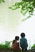 Girl and boy fishing on lake shore