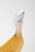 A banana with the stem wrapped in cling-film to keep if fresh for longer