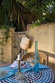 Wine glass and bottle on tiled table in front of garden wall