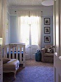 Blick durch offene Tür auf Vintage Kinderbett an Terrassentür mit gerafftem Vorhang in traditionellem Ambiente