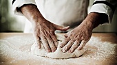 A chef kneading pizza dough