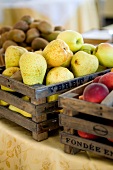 A wooden box of pears, between a box of nectarines and one of kiwis