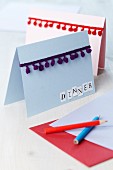 Invitation cards decorated with pompom trim