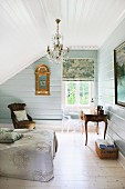 Attic bedroom with chandelier, gilt-framed mirror and antique furnishings