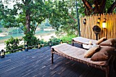 Wooden sun loungers with mattresses and pillows on twilight terrace