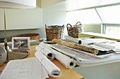 Papierrollen und Pläne auf Schreibtisch im Büro