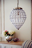 Teardrop-shaped lamp with vase of flowers on cabinet in background