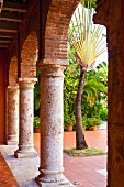 Peaceful arcade with rounded arches and view into courtyard with lush foliage