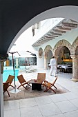 View of pool and outdoor furniture in Oriental hotel courtyard through rounded arch